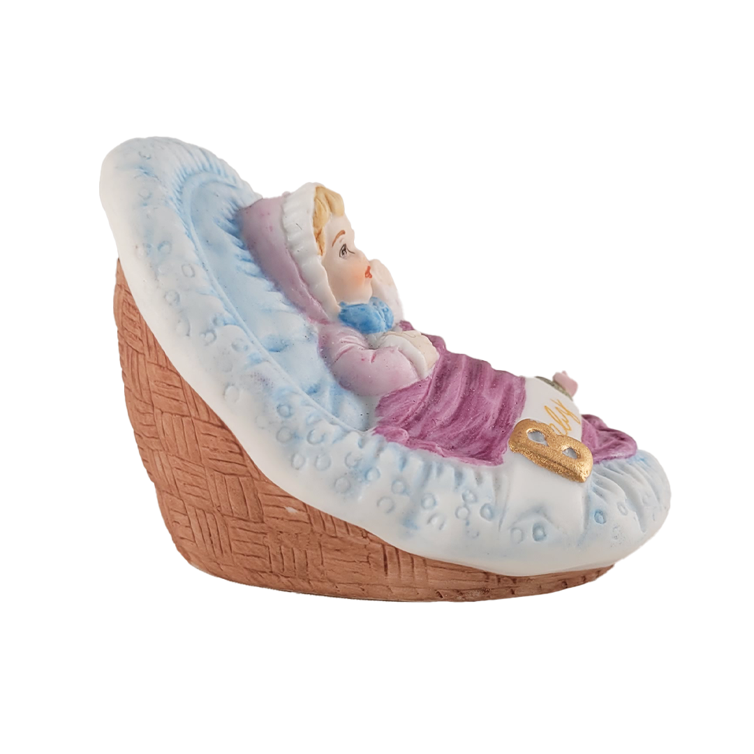 Side of figurine of a baby in a basket with a white background