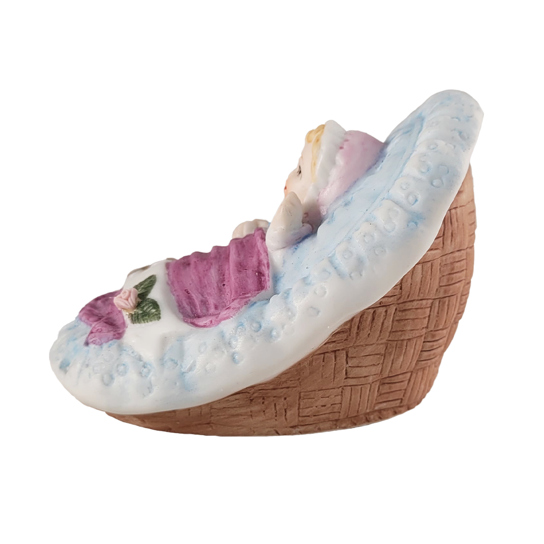 Side of figurine of a baby in a basket with a white background