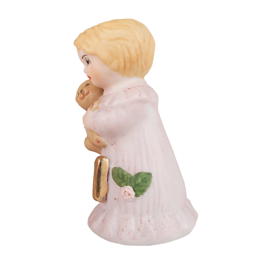 Side of figurine of a woman holding a teddy bear on a white background