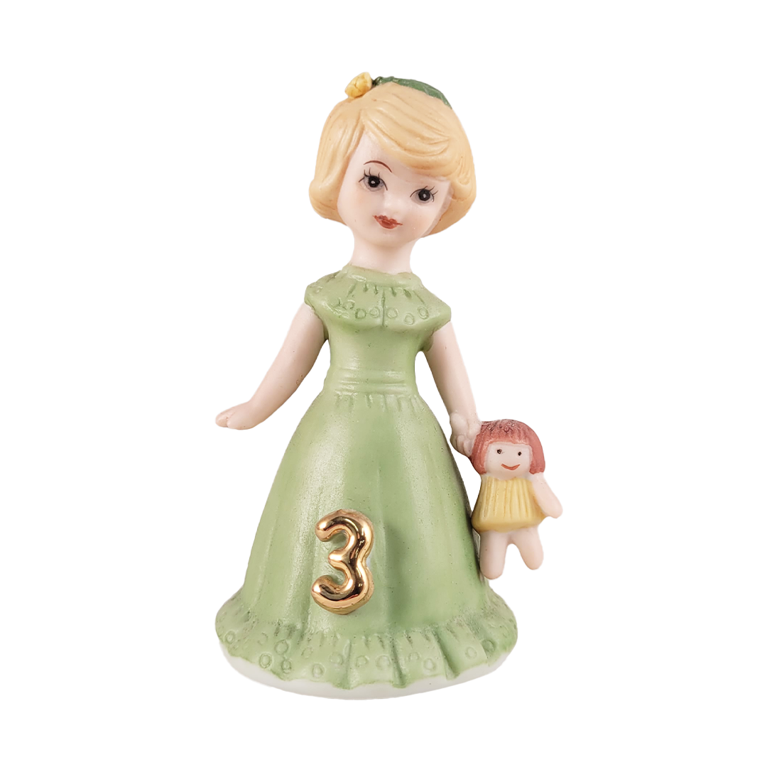 girl figurine in green dress holding doll on white background