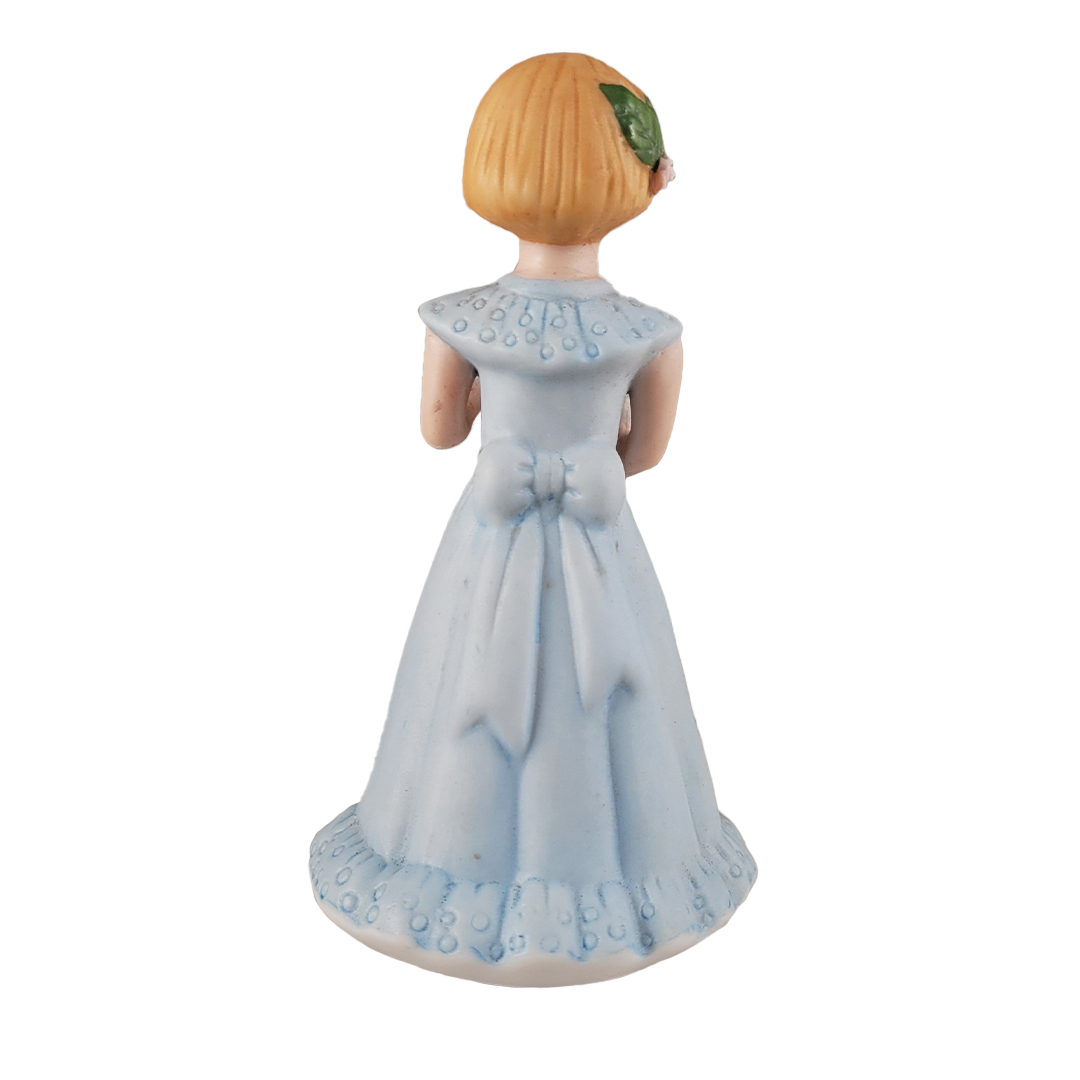 Back of figurine of a girl in a light blue dress with a white background
