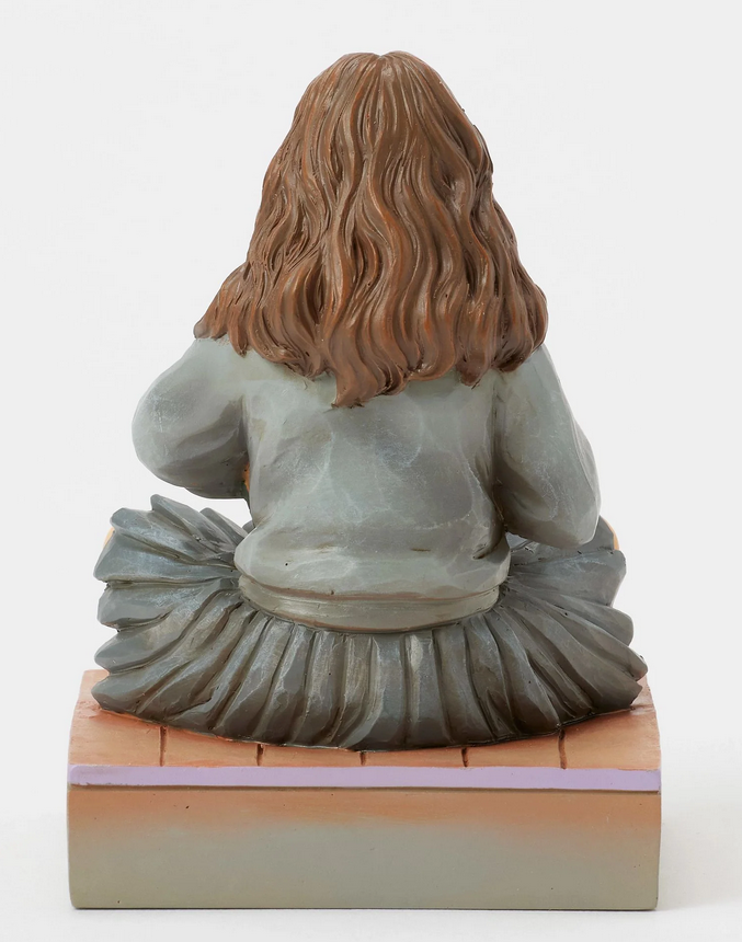 Back of figurine of a Hermine Granger in a school uniform holding books on a decorative base with owl designs.