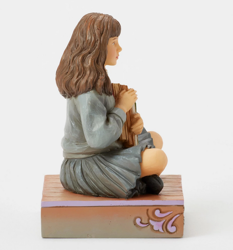 Left side of figurine of a Hermine Granger in a school uniform holding books on a decorative base with owl designs.