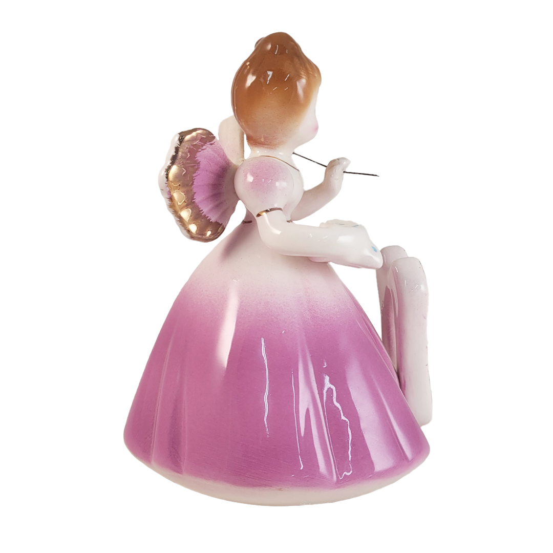 side of angel figurine wearing a purple dress on a white background