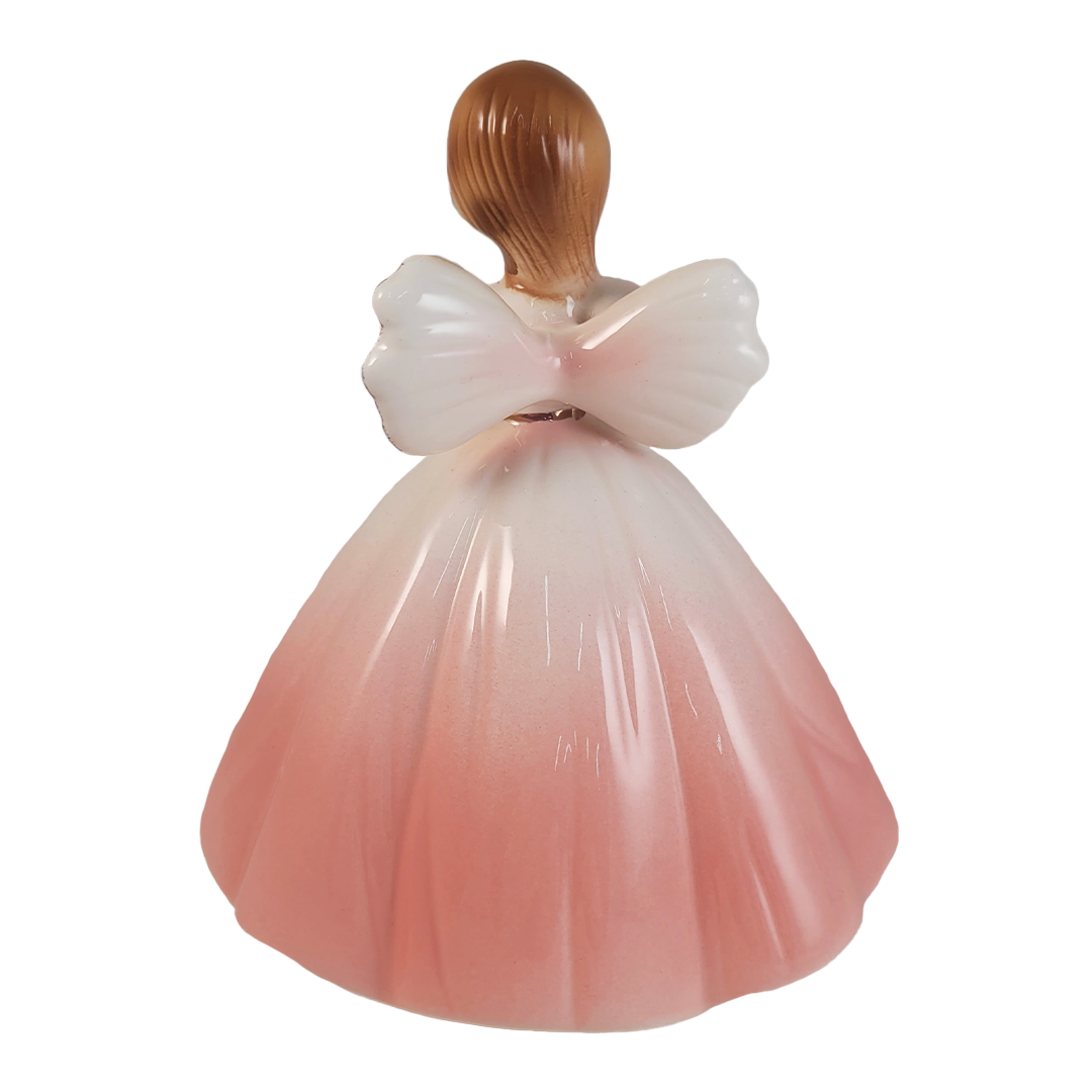 Back of angel figurine in a light pink dress on a white background