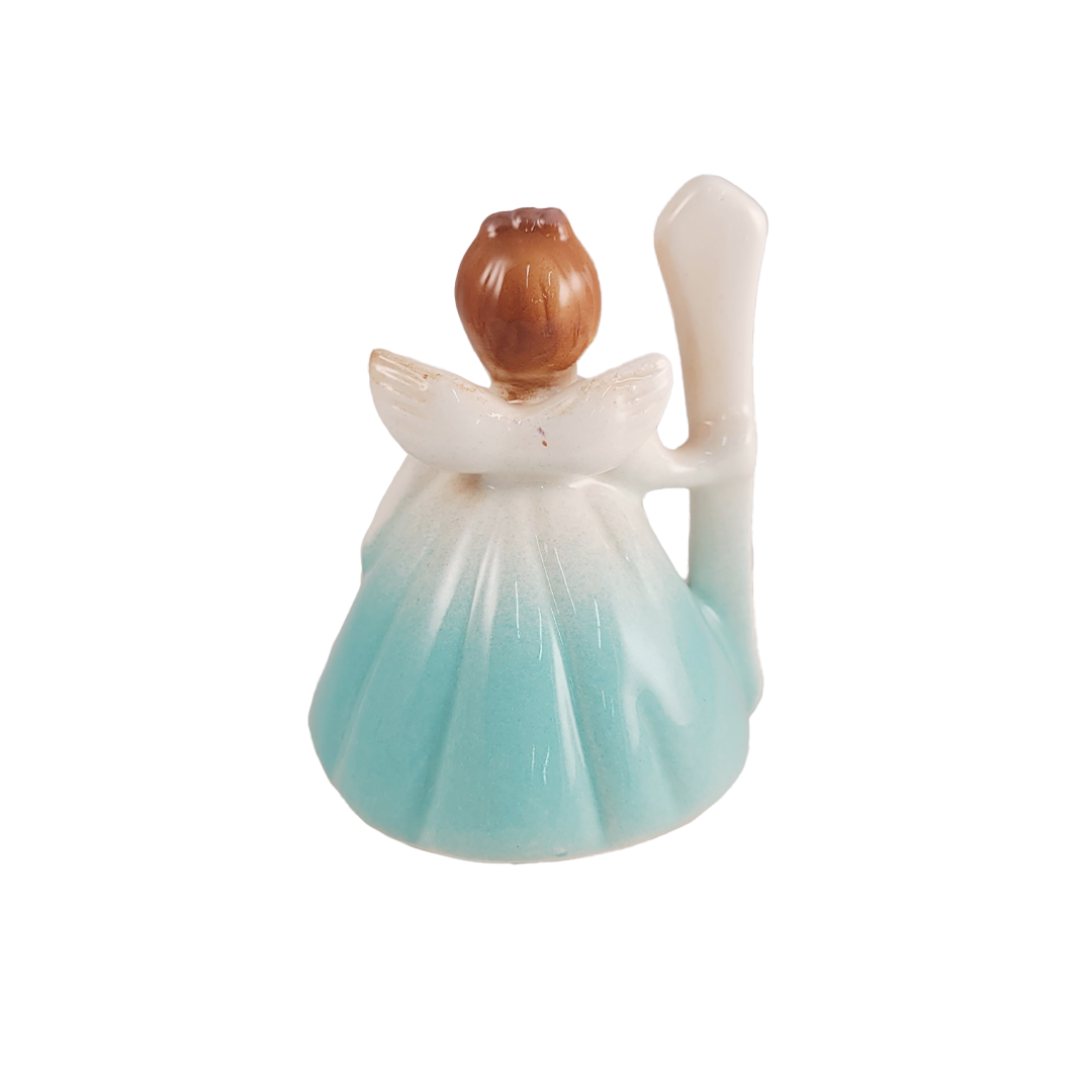 Back of small angel figurine with a brown head and light blue dress on a white background