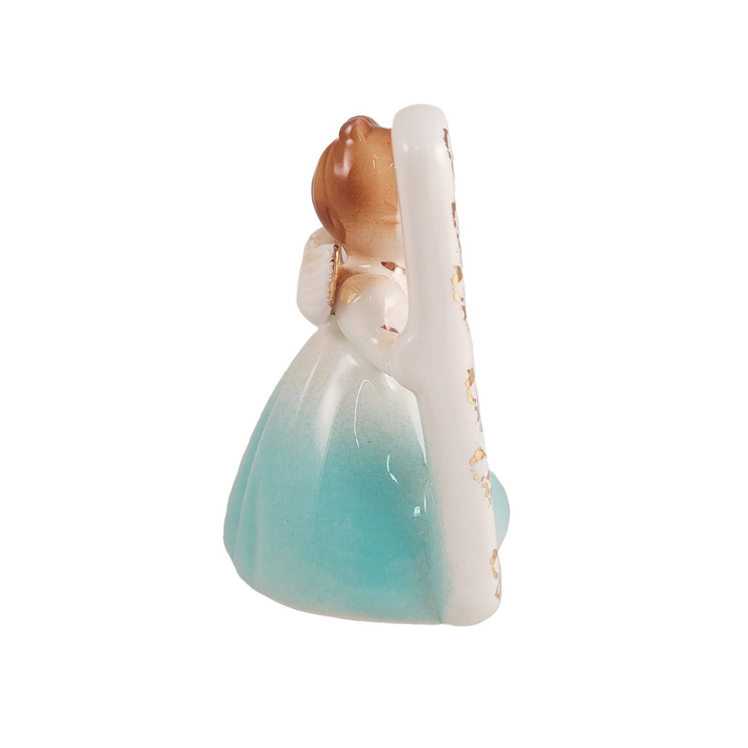 Side of small figurine of a angel with a blue dress on a white background