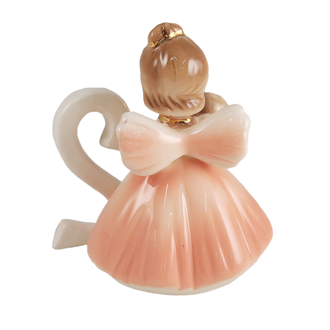 back of angel figurine in peach dress on a white background