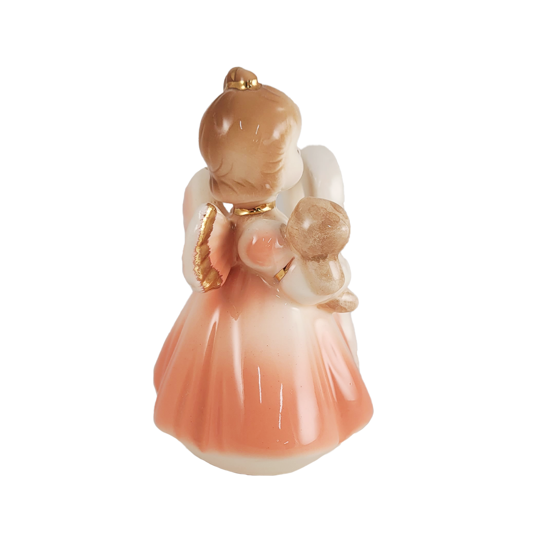 Side of decorative figurine of a girl angel holding a teddy bear on a white background