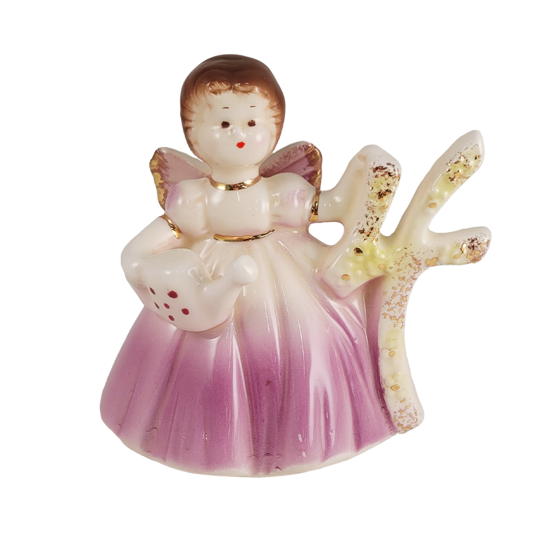 Small angel figurine with pink dress and brown hair holding a number 4 and tea pot on a white background