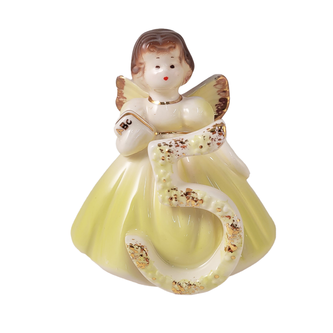 Front of ceramic angel figurine with a yellow dress and number 5 on a white background