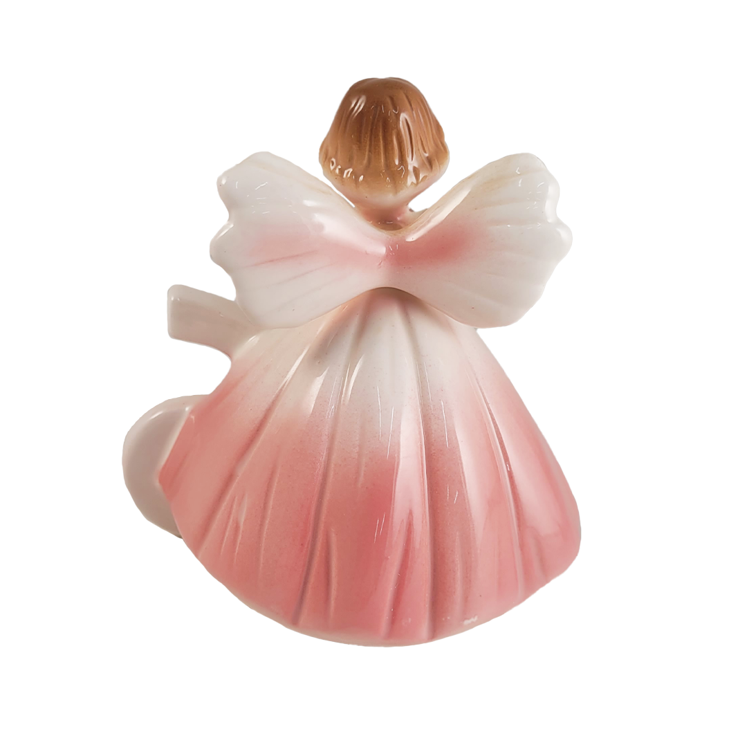 Back of ceramic angel figurine with a pink dress on a white background
