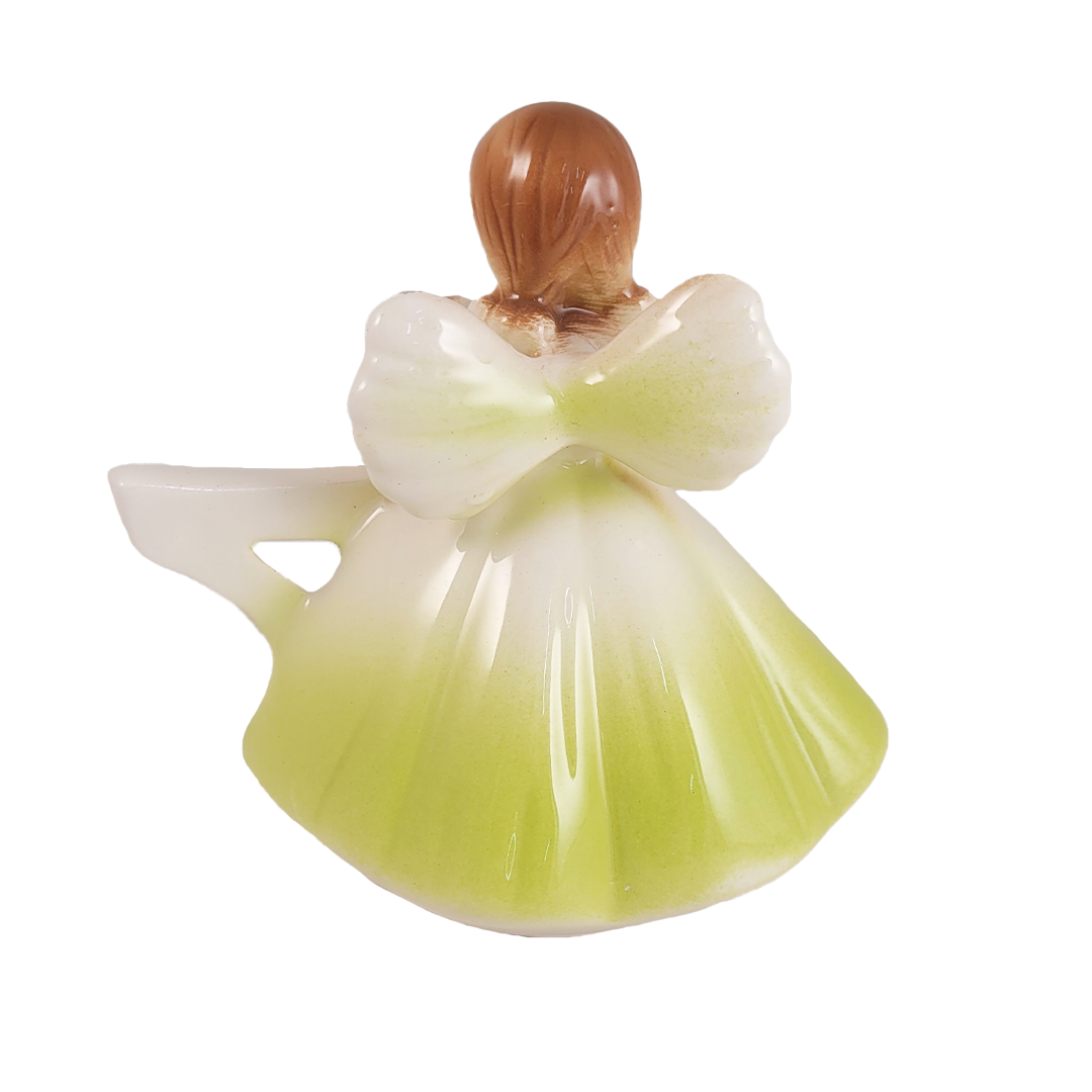 Back of angel figurine in a lime green dress on a white background