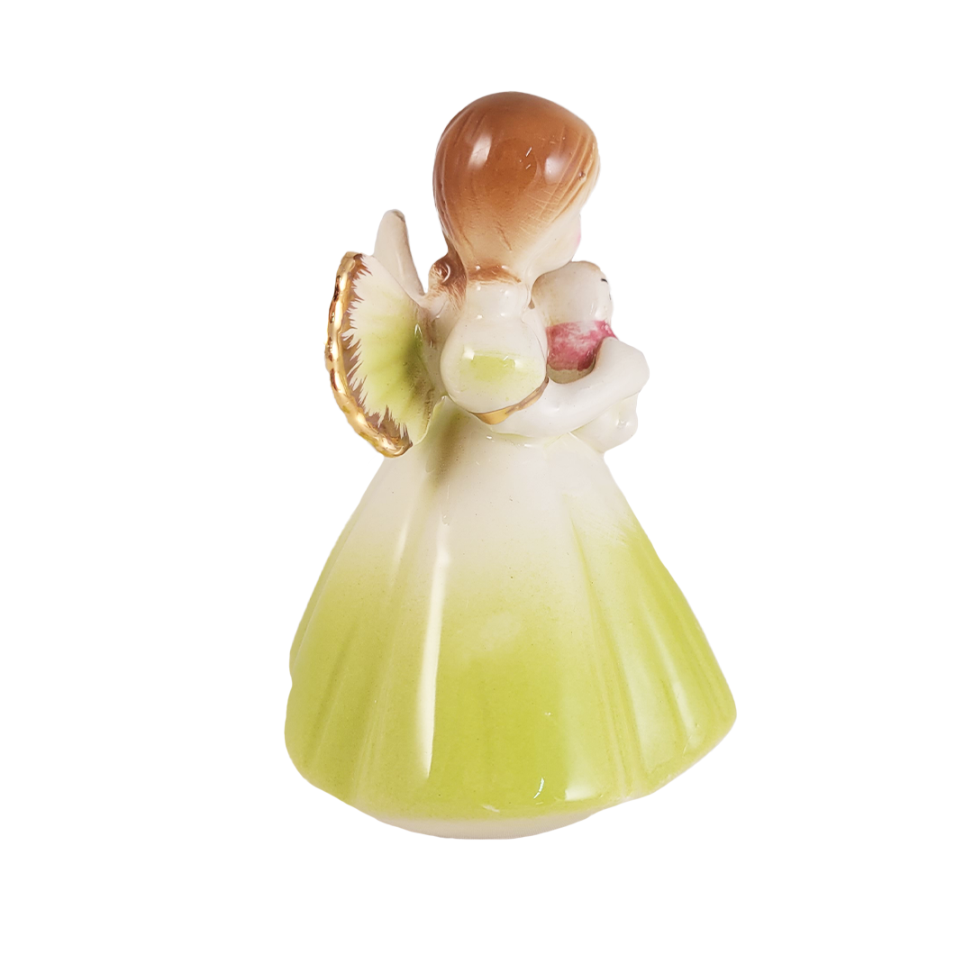 Side of porcelain angel figurine with a green dress and brown hair on a white background