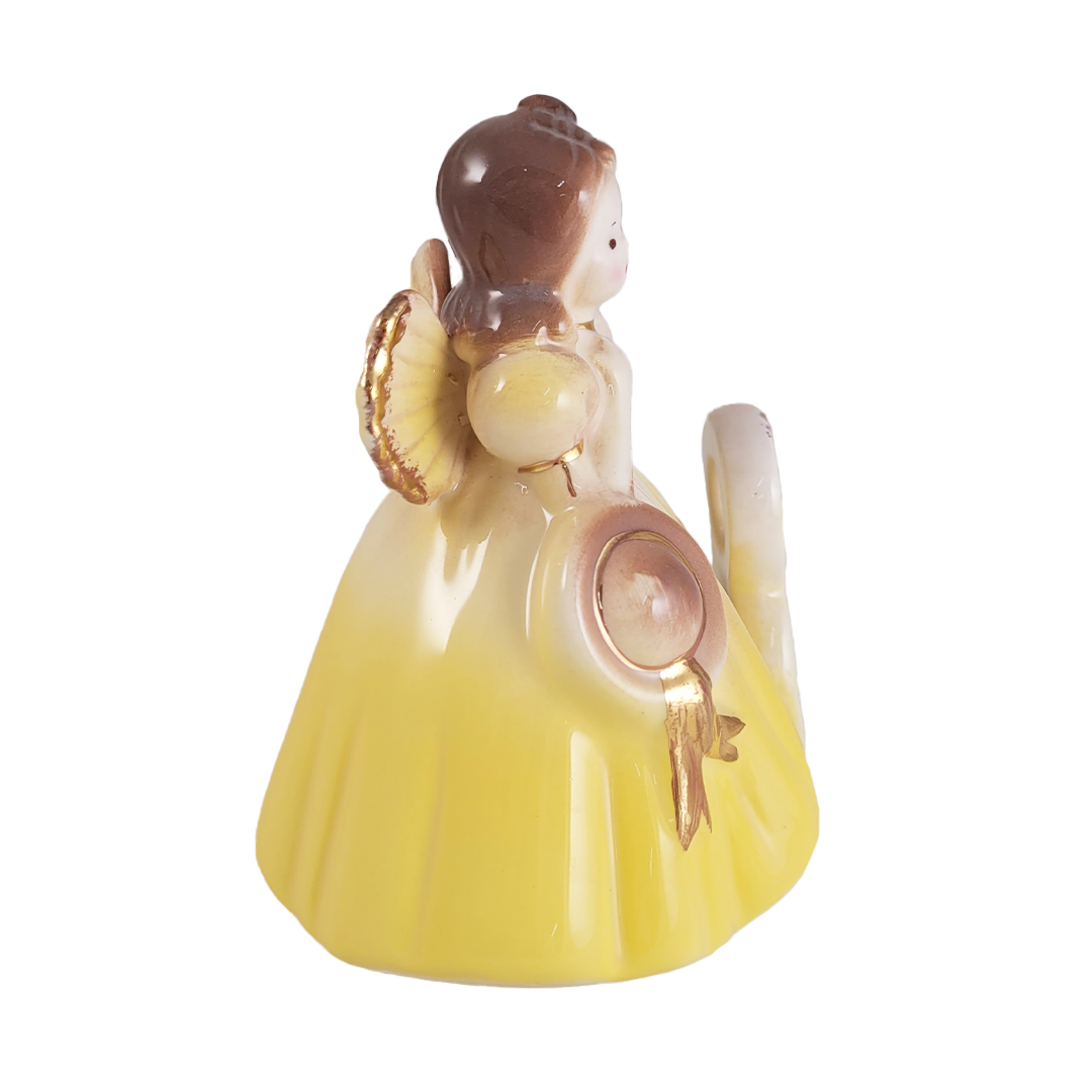 Side of angel figurine with a yellow dress on a white background
