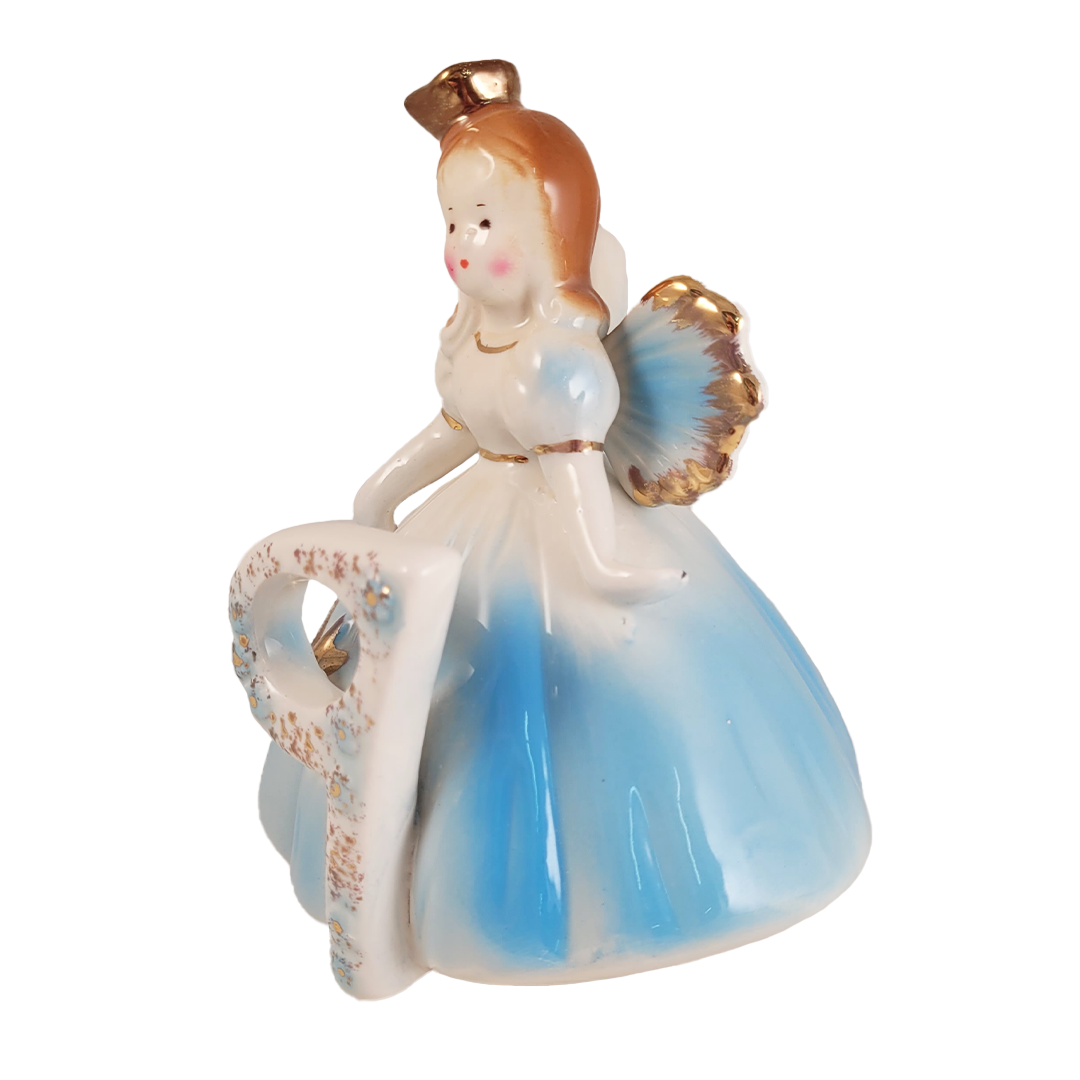 Side of angel figurine in a blue dress with gold accents on a white background