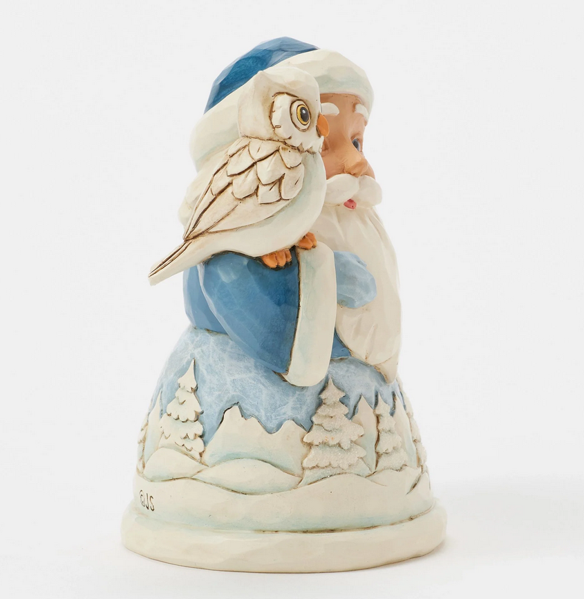 Side of decorative figurine of a Santa Claus with an owl on his shoulder, with a snowy landscape robe.