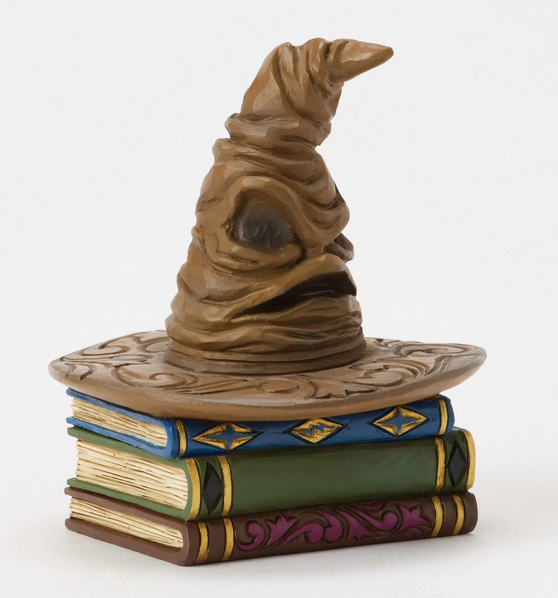 Quarter of figurine of a Sorting Hat on top of books with decorative covers on a white background
