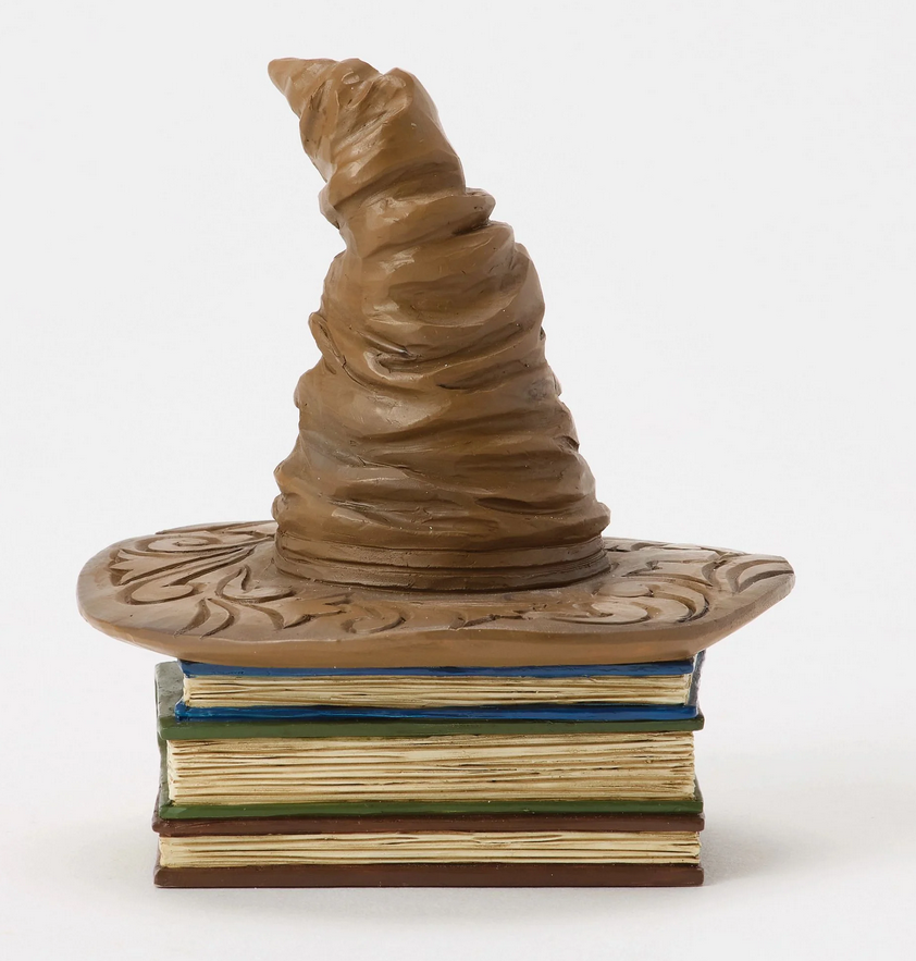 Back of figurine of a Sorting Hat on top of books with decorative covers on a white background