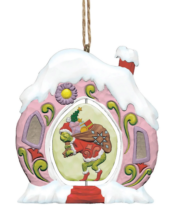 Decorative Christmas ornament featuring the Grinch in a pink house with snow on the roof.