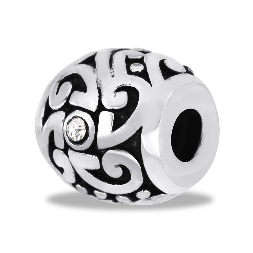 A silver metal bead with a geometric pattern and a central clear crystal