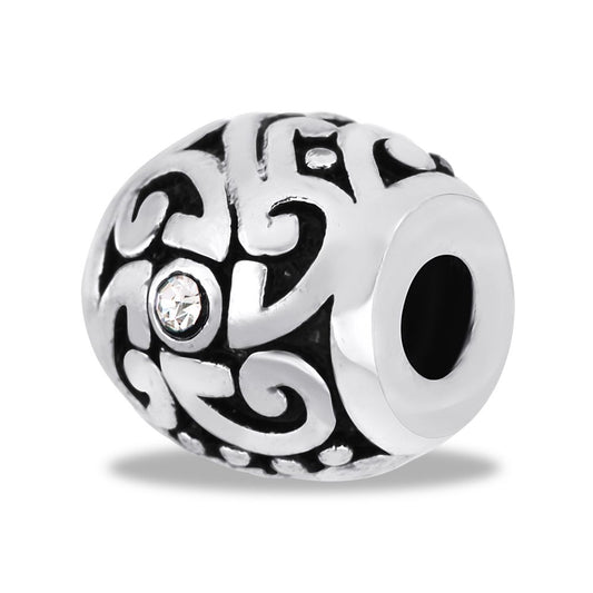 A silver metal bead with a geometric pattern and a central clear crystal