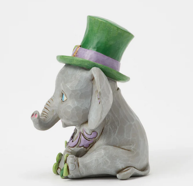 Side of elephant figurine wearing a green top hat on a white background