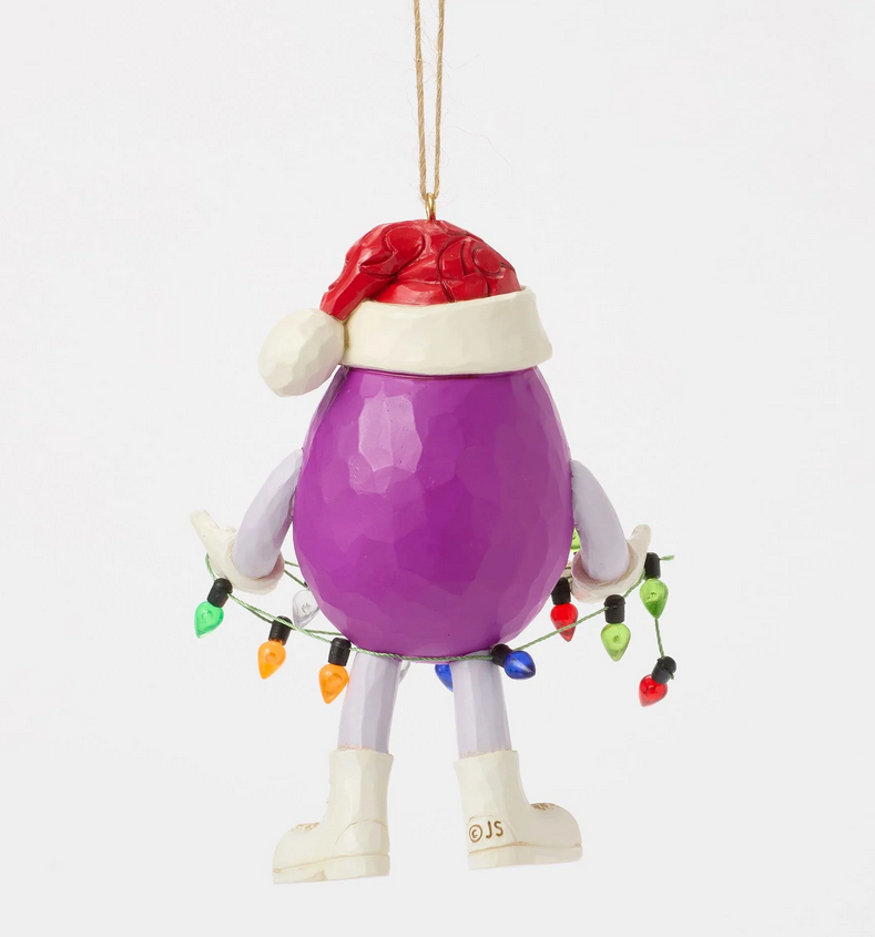 Back of purple M&M character ornament wearing a Santa hat holding Christmas lights on a white background