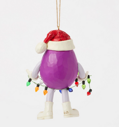 Back of purple M&M character ornament wearing a Santa hat holding Christmas lights on a white background