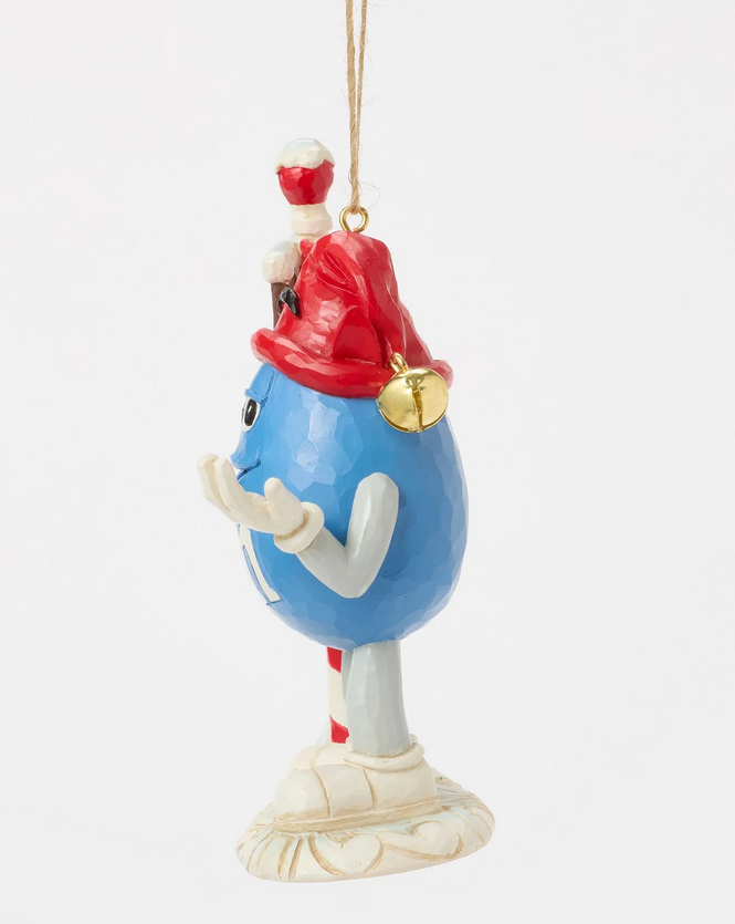 Side of decorative ornament of a blue M&M character with a red hat on a white background