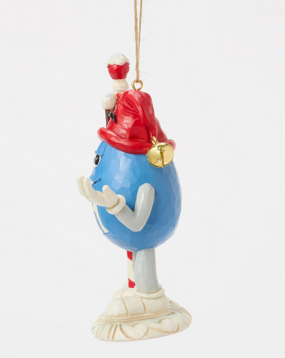 Side of decorative ornament of a blue M&M character with a red hat on a white background