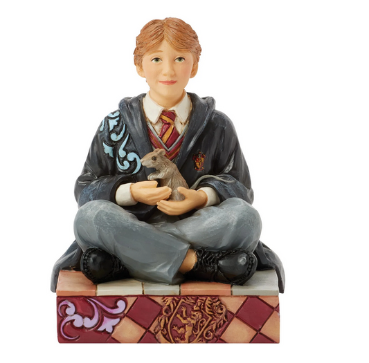 Front of figurine of Ron Weasley in a robe holding a rat, sitting on a box with Gryffindor emblem.