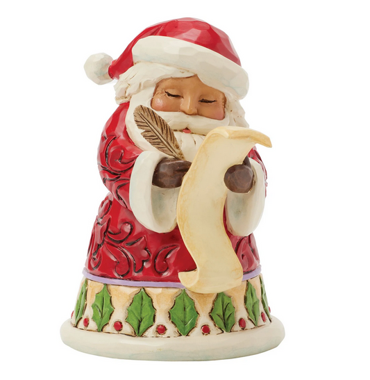 Front of Santa Claus figurine holding a feather and quill on a white background