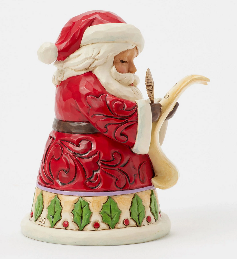 Right side of Santa Claus figurine holding a feather and quill on a white background