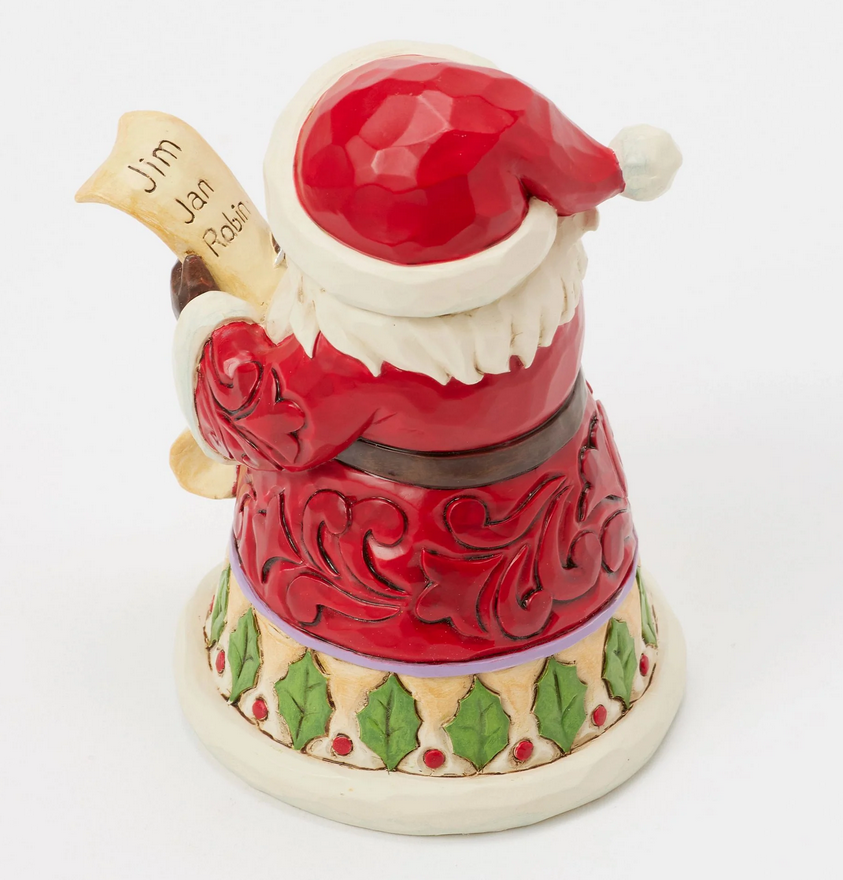 Top down view of Santa Claus figurine holding a feather and quill on a white background