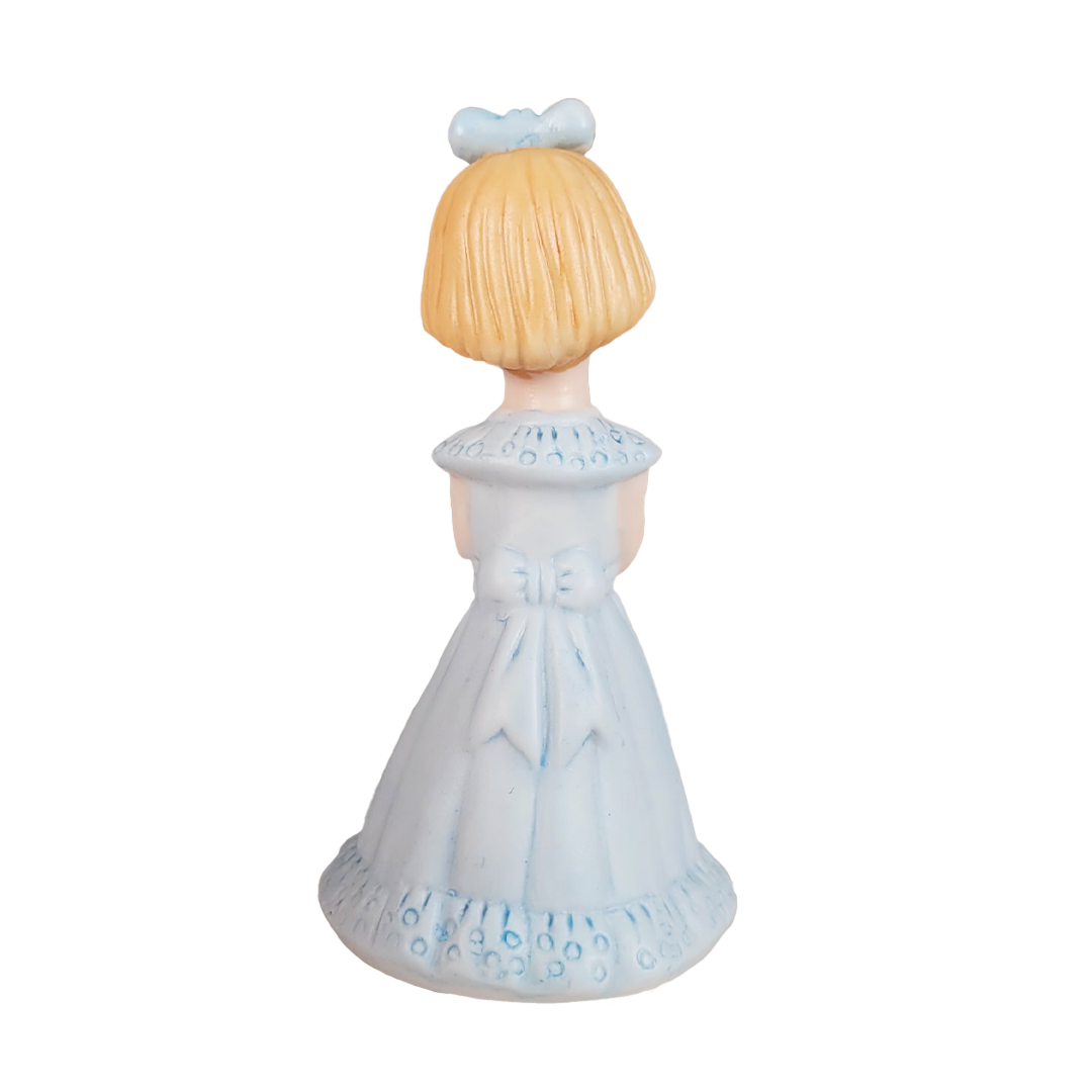 Back of figurine of a girl in a blue dress with a blue bow on a white background