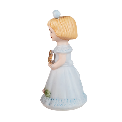 Side of figurine of a girl in a blue dress with a blue bow on a white background