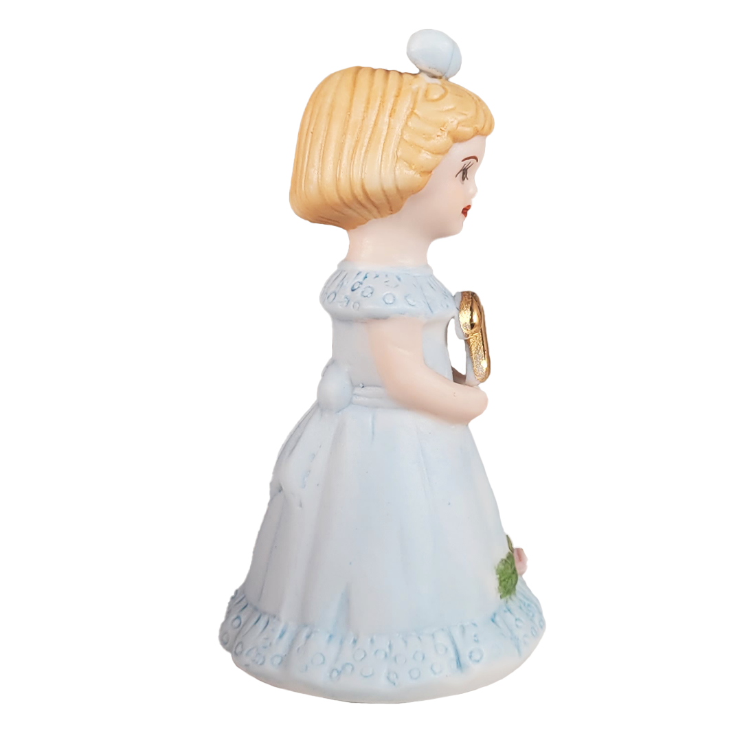Side of figurine of a girl in a blue dress with a blue bow on a white background
