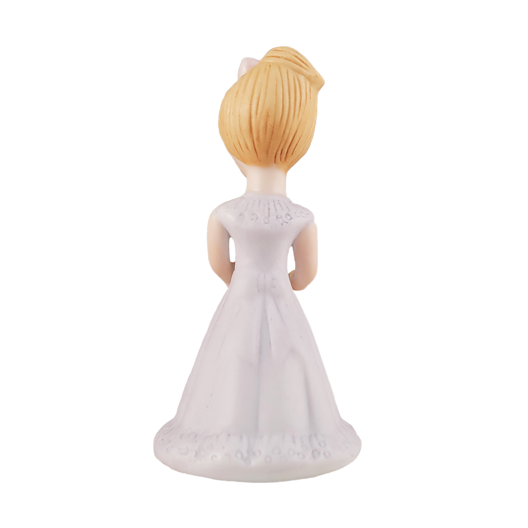 Back of figurine of a woman in a white dress with blonde hair on a white background