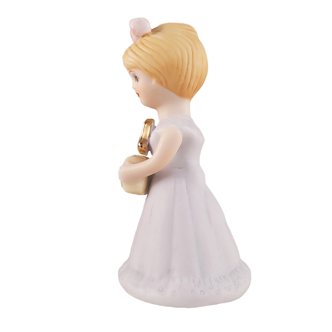 Side of figurine of a woman in a white dress with blonde hair on a white background