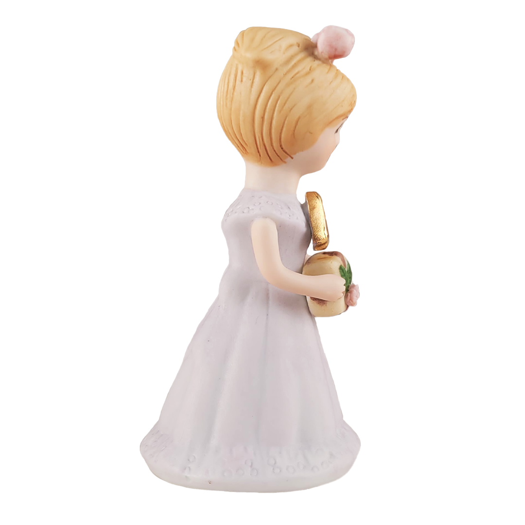 Side of figurine of a woman in a white dress with blonde hair on a white background