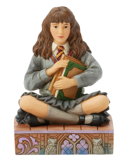 Front of figurine of a Hermine Granger in a school uniform holding books on a decorative base with owl designs.
