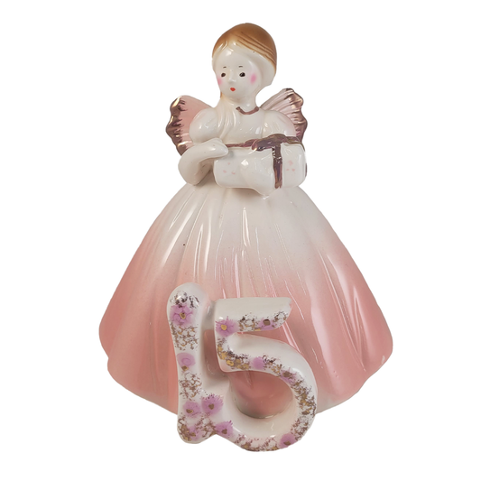 Front of angel figurine holding a present in a light pink dress with a number 15 on a white background