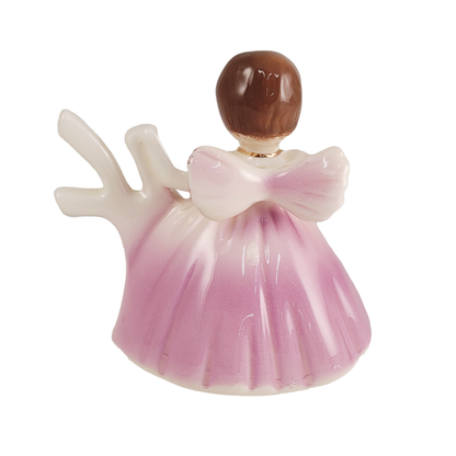 Back of small angel figurine with a pink dress on a white background