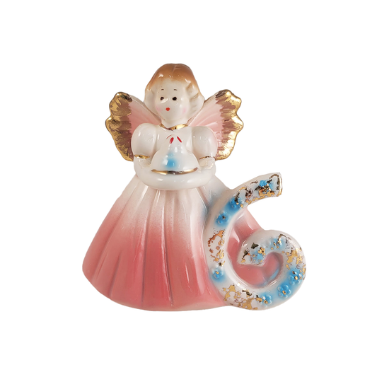 Front of decorative angel figurine with a pink dress and gold wings holding a cake and a number 6 on a white background