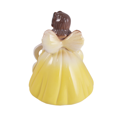 Back of angel figurine in a yellow dress with a brown head on a white background