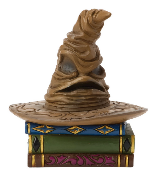 Front of figurine of a Sorting Hat on top of books with decorative covers on a white background