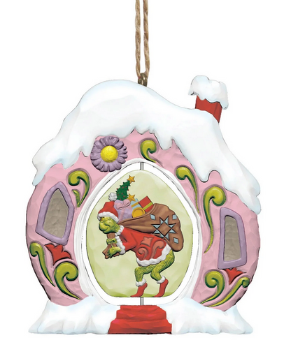 Decorative Christmas ornament featuring the Grinch in a pink house with snow on the roof.